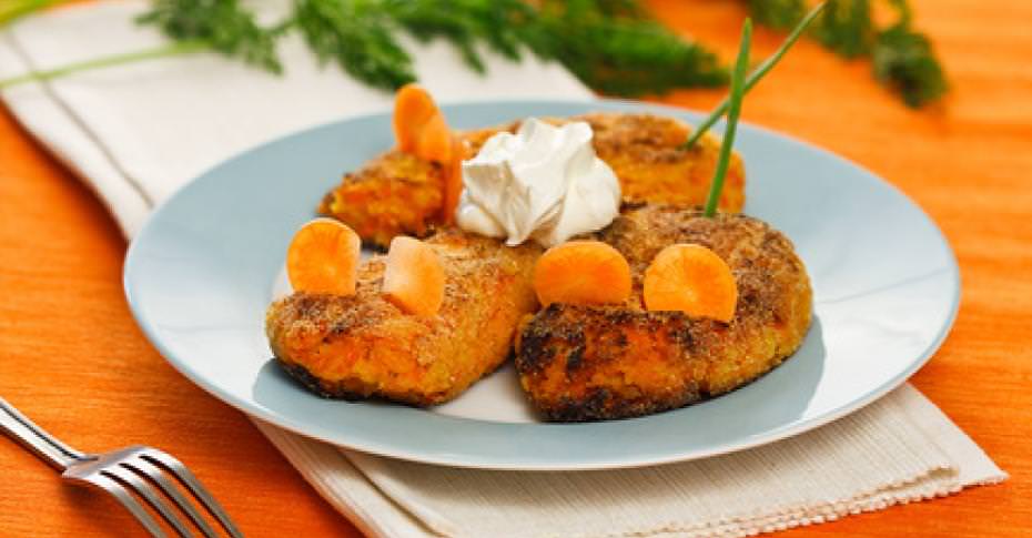 Изображена тарелка с картофельно  морковными котлетами и сметаной