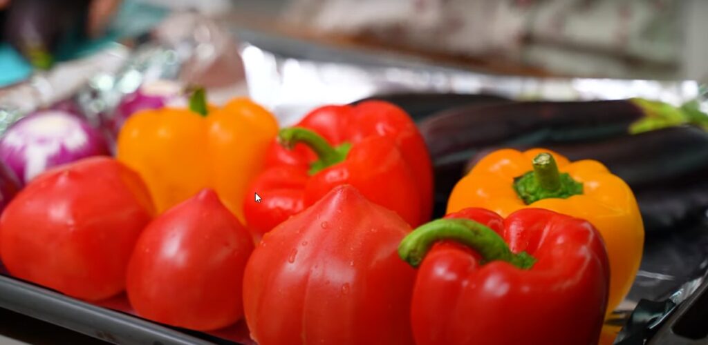на металлическом протвине на фольге расположены овощи 4 болгарских перца 3 помидорки для Теплого салата с баклажанами